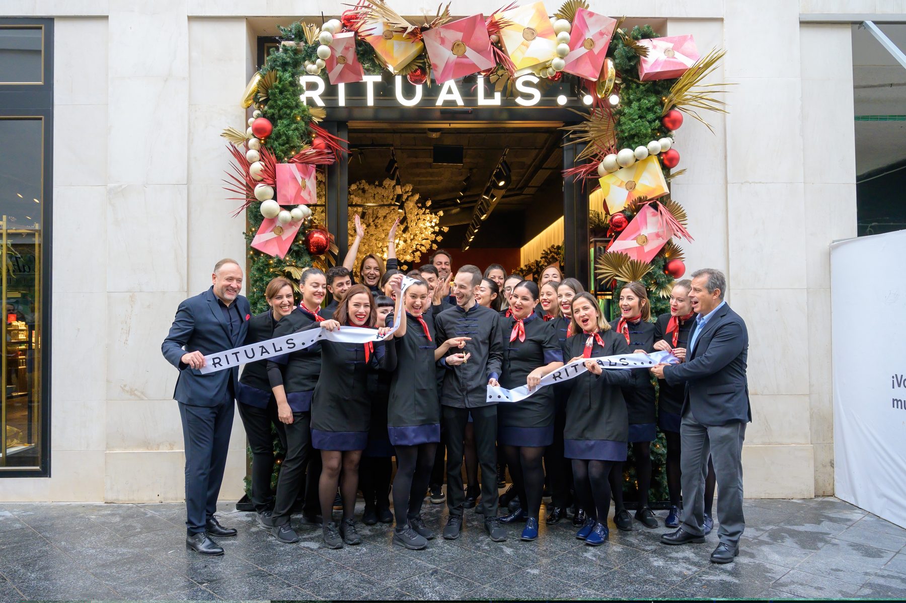 Equipo de una tienda en la inauguración, con la cinta y la fachada decorada