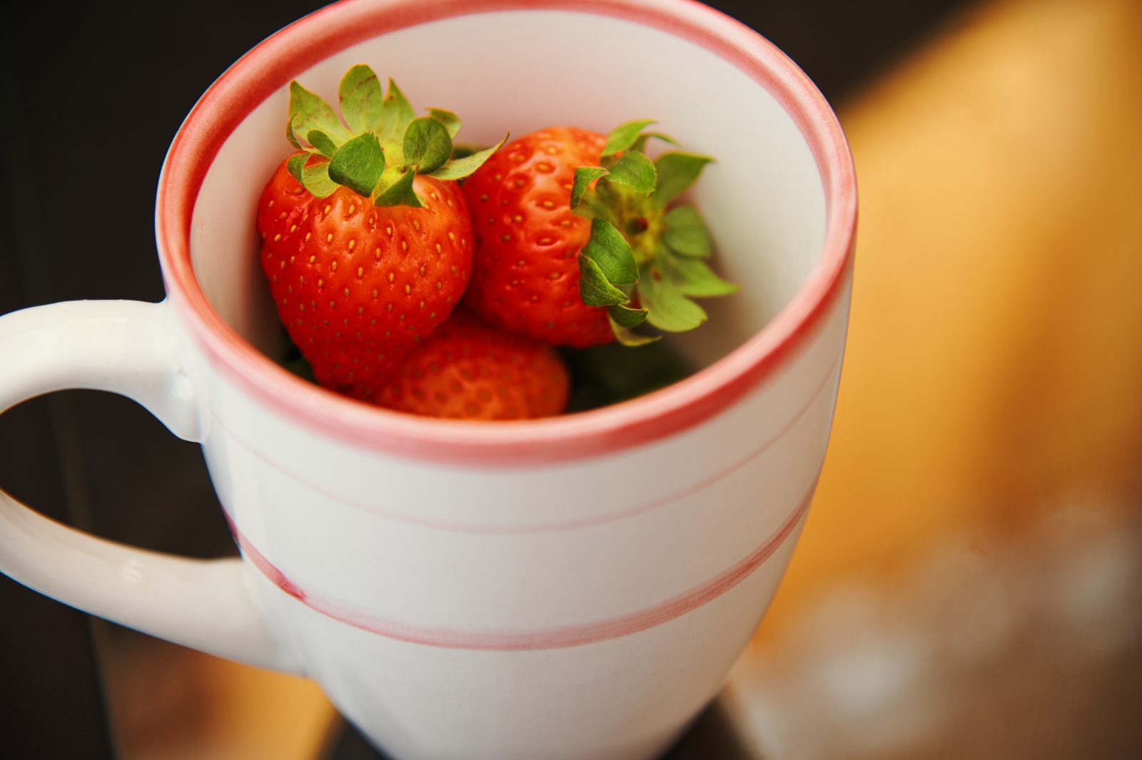 Fresas frescas dentro de una taza de cerámica blanca con borde rosa
