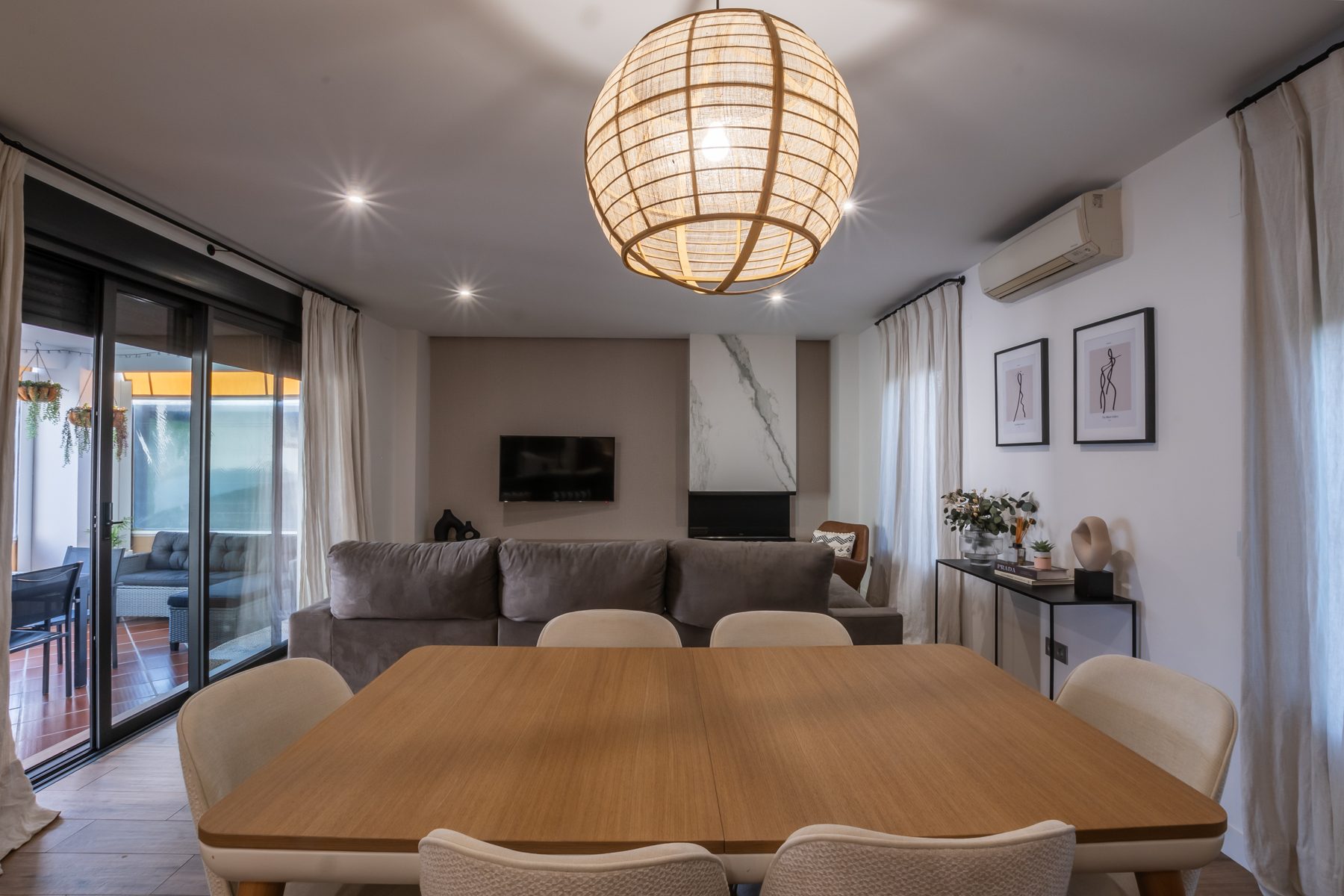 Salón comedor moderno con mesa de madera, sofá y lámpara de mimbre