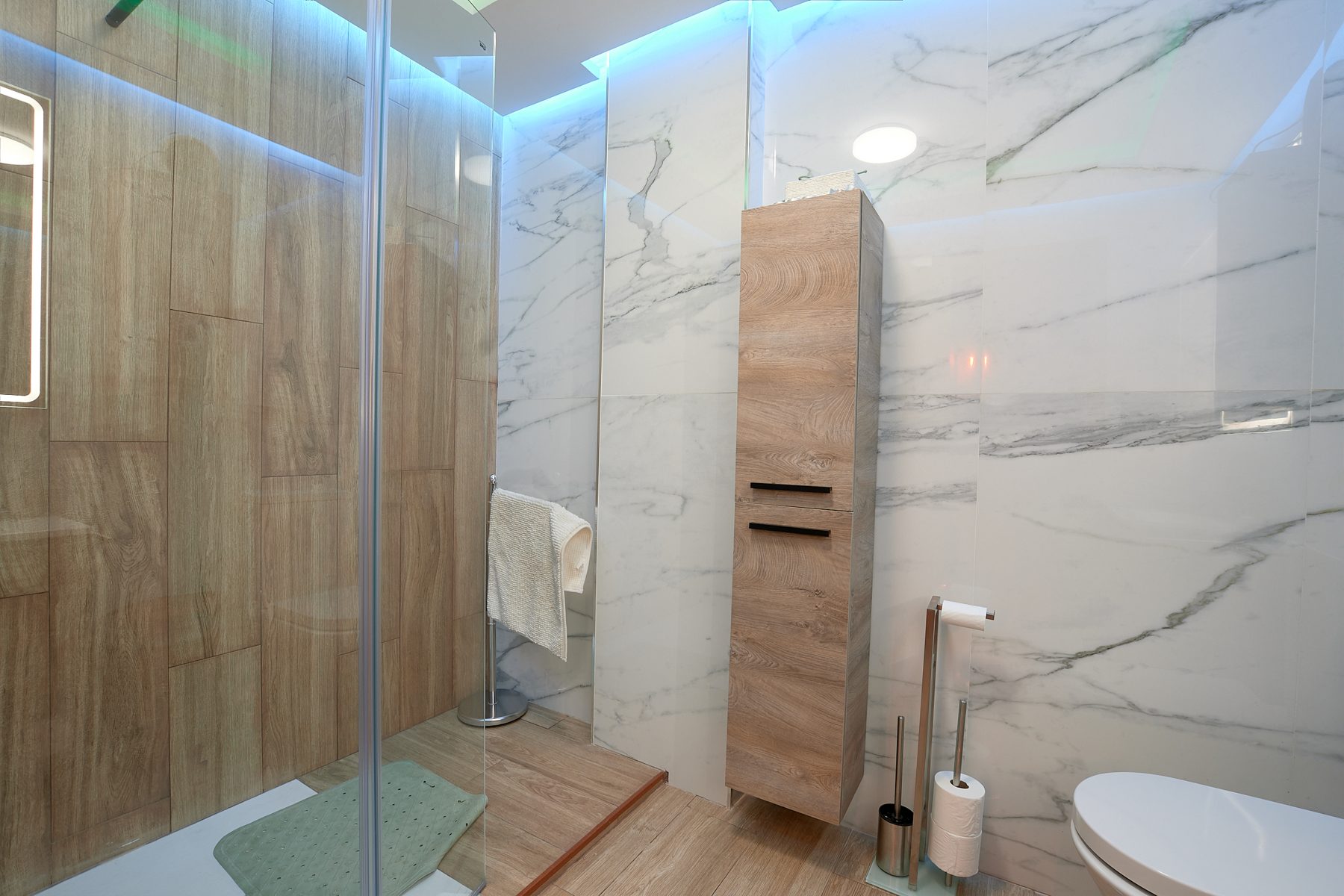 Baño moderno de mármol con ducha iluminada