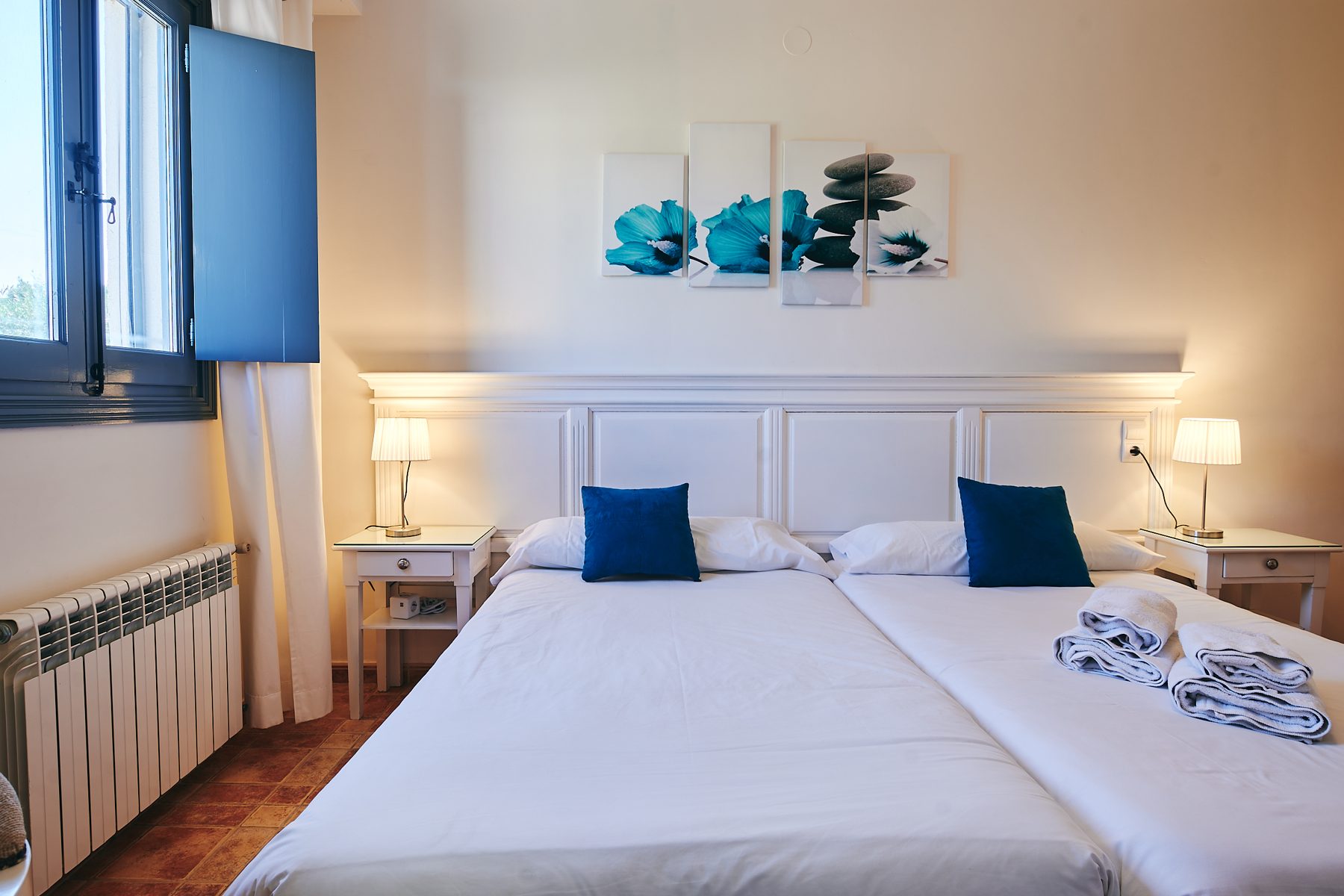 Dormitorio luminoso con camas blancas y cojines azules