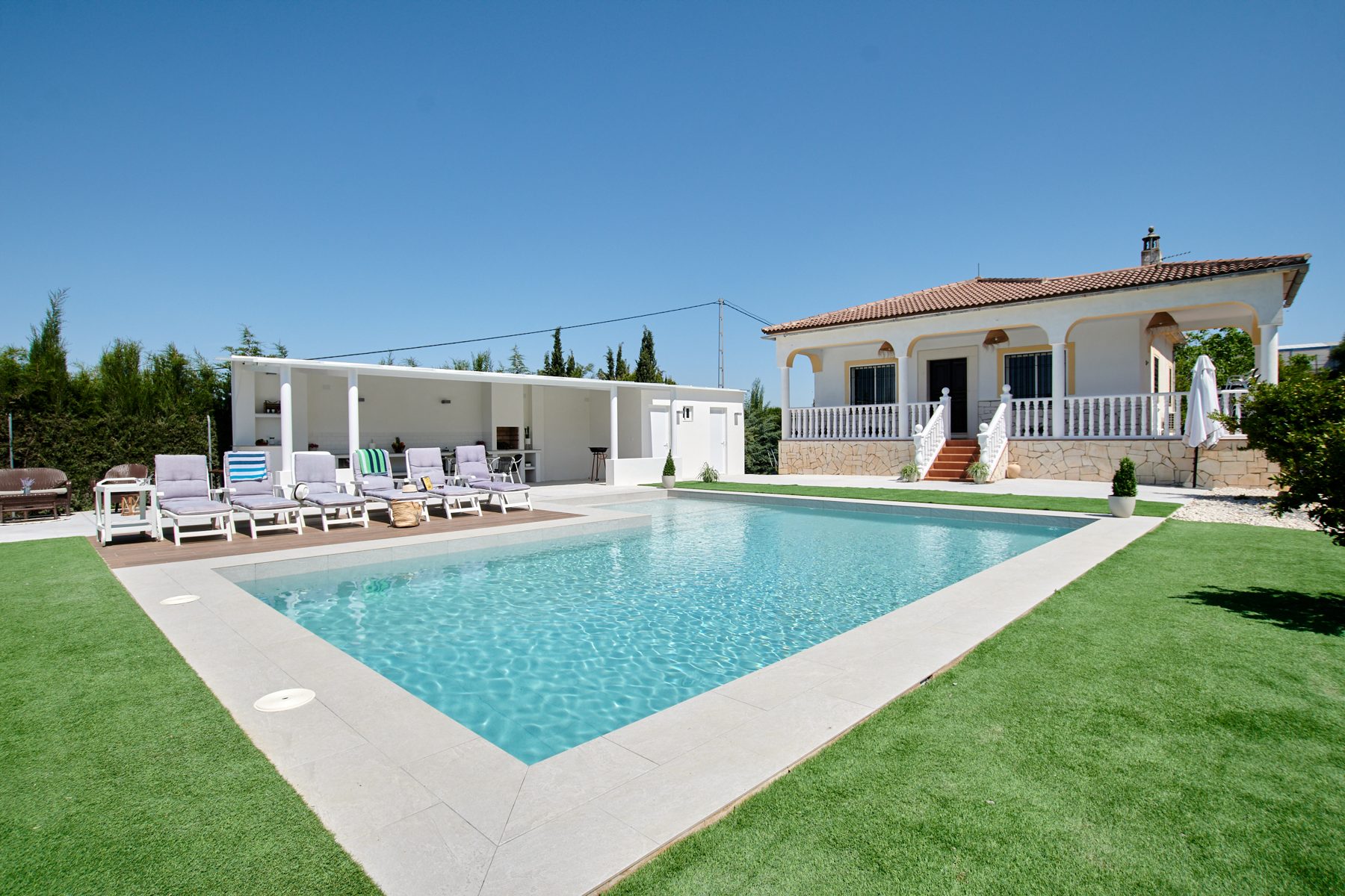 Chalet con piscina, césped y tumbonas